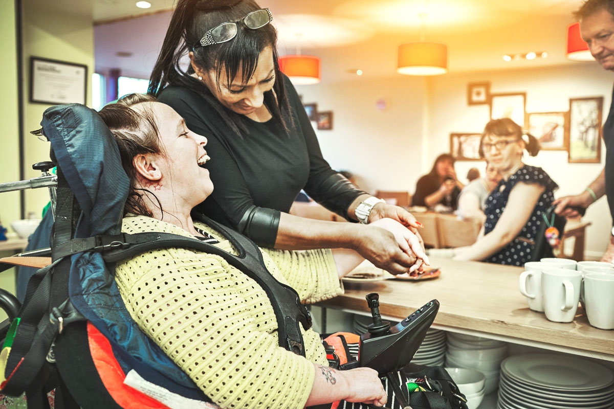 Wheelchair down syndrome disability girl patient in clinic or hospital with nurse or professional healthcare worker. Nursing and medical caregiver helping happy, friendly and young disabled person