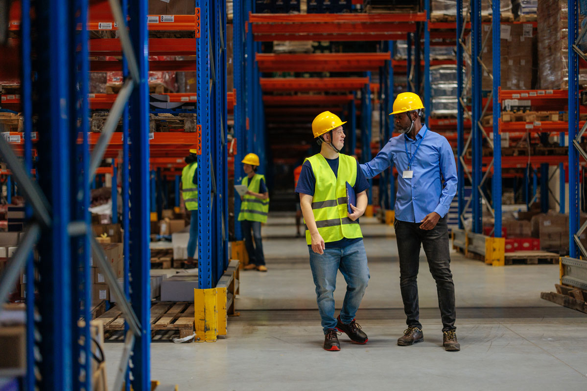 Manager supporting young warehouse worker with down syndrome